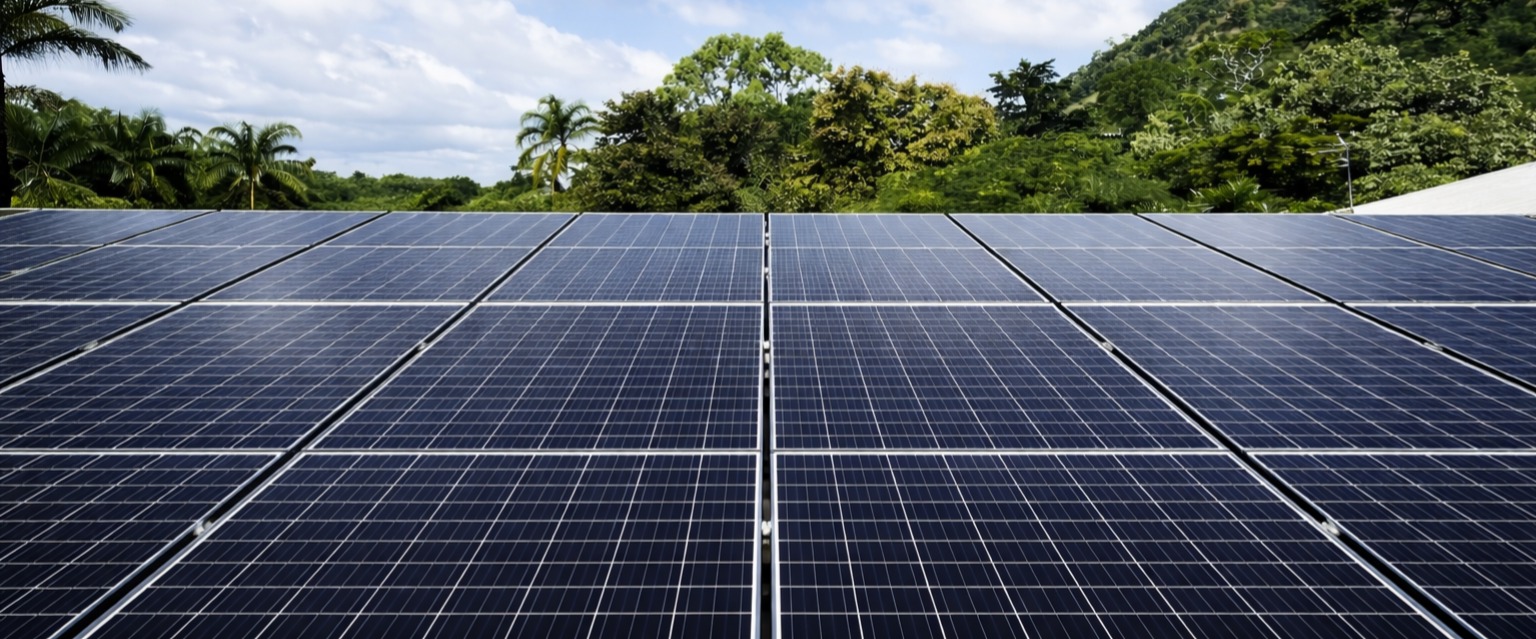 Rows of solar panels on a residential metal roof, with a rocky hill in the background